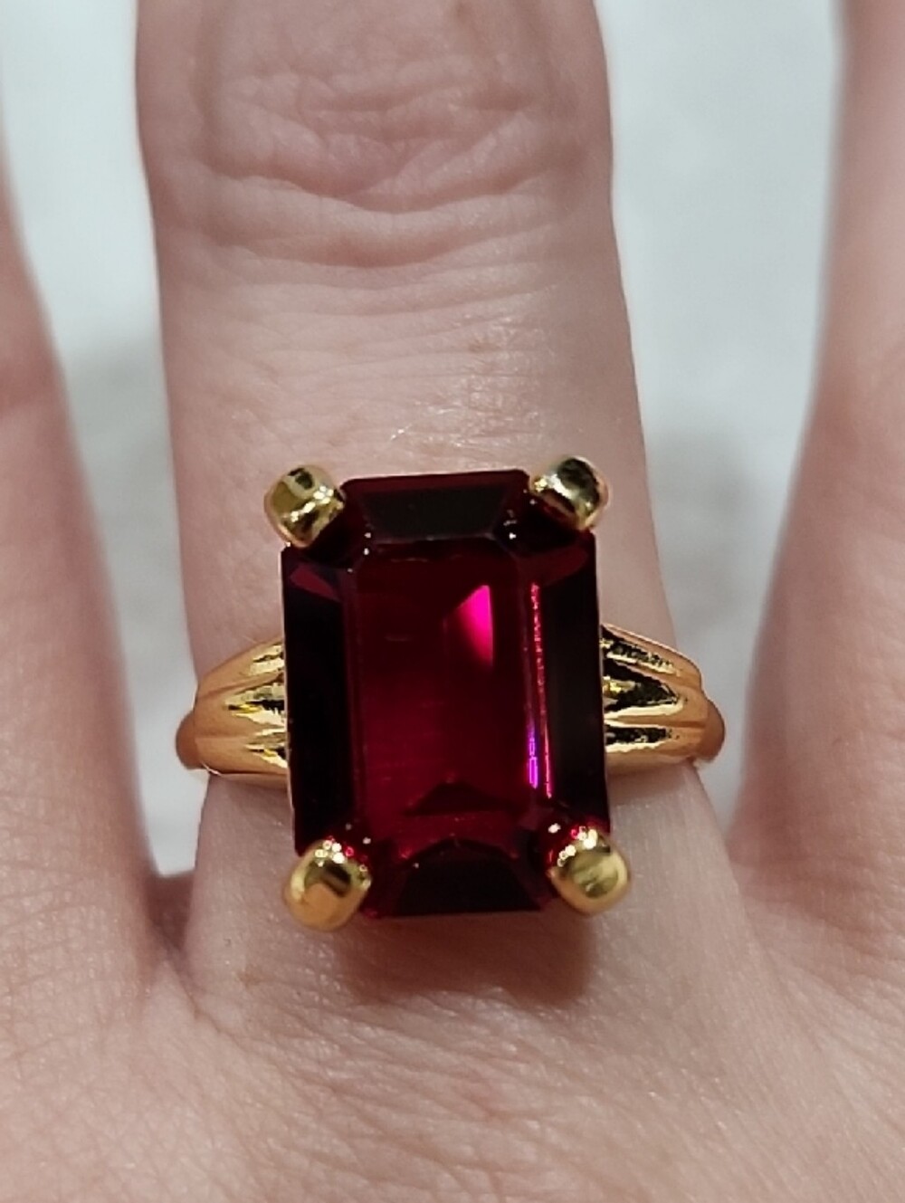 GOLD-PLATED RING WITH DEEP RED EMERALD-CUT STONE